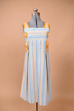 Load image into Gallery viewer, Vintage handmade blue and orange striped dress is shown from the front. This dress has an abstract embroidered orange and white ribbon.
