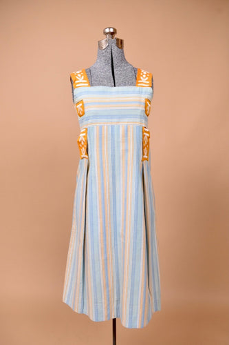 Vintage handmade blue and orange striped dress is shown from the front. This dress has an abstract embroidered orange and white ribbon.