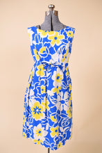 Load image into Gallery viewer, Vintage 1960&#39;s blue and yellow bright floral print sleeveless midi dress is shown from the front. This dress has an empire waist with a bow. 
