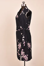 Load image into Gallery viewer, Vintage black and pastel purple floral print dress is shown from the side. This wrap dress is sleeveless.