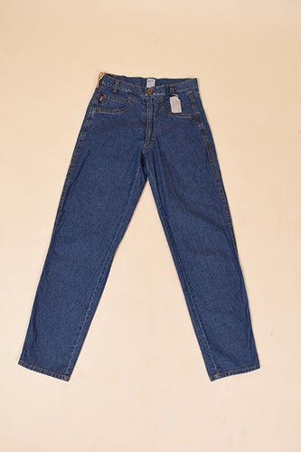 Vintage 1980's medium wash navy denim boyfriend jeans by Emmegi are shown from the front. These thin worn denim jeans have a tapered leg. 