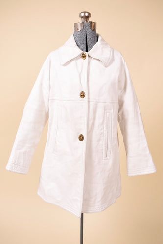 Vintage 60's white leather swing coat by Sills Bonnie Cashin is shown from the front. This white leather swing coat has brass turn locks down the front. 