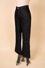 Load image into Gallery viewer, Vintage Jordache black denim dark wash flares are shown from the side. These bell bottom jeans have studs down the side. 
