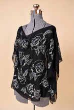 Load image into Gallery viewer, Vintage black sheer drapey handkerchief blouse by White House Black Market is shown from the side. This blouse has white beaded rose flower designs. 
