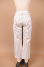 Load image into Gallery viewer, Vintage white low rise striped flare pants by Theory are shown in close up. These pants have a cropped flare fit. 

