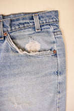 Load image into Gallery viewer, VIntage seventies orange tab distressed long Levi&#39;s shorts are shown in close up. 
