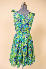 Load image into Gallery viewer, Vintage blue and green flower print dress with a full pleated skirt is shown from the back. 
