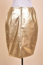 Load image into Gallery viewer, Vintage deadstock gold NWT nineties leather skirt by Kenar is shown from the back. This skirt has a zipper on the back.  
