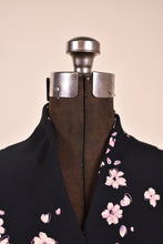 Load image into Gallery viewer, Vintage black and pink floral print dress is shown in close up. This dress has a raised collar with a v neckline.