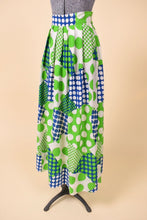 Load image into Gallery viewer, Vintage 60s bright blue and green polka dot maxi skirt is shown from the side. This maxi skirt has a flowy pleated fit. 
