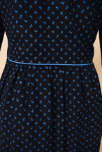 Load image into Gallery viewer, Vintage black cotton floral midi length dress by Lanz is shown in close up. This 70's dress has light blue piping at the waistline.