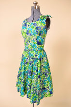 Load image into Gallery viewer, Vintage 60's blue and green flower print fit n flare day dress is shown from the side. This dress is tailored at the waist with a circle skirt.