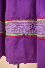 Load image into Gallery viewer, Vintage made in India purple cotton tunic midi dress is shown in close up. This dress has embroidered trim at the bottom hem.
