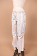 Load image into Gallery viewer, Vintage low rise striped trousers by Theory are shown from the side. These blue and tan striped pants have a flare fit. 
