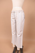 Load image into Gallery viewer, Vintage low rise striped trousers by Theory are shown from the side. These blue and tan striped pants have a flare fit.