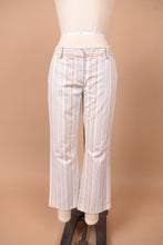 Load image into Gallery viewer, Vintage white stripe low rise pants by Theory are shown from the front. These pants have a cream, tan, and blue vertical stripe.