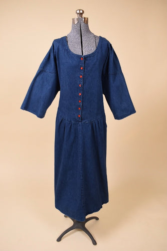 Vintage 1980s union-made buttoned navy denim dress is shown from the front. This dark wash denim dress has red plastic buttons down the front. 