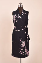 Load image into Gallery viewer, Vintage 1990s black and purple floral print mini wrap dress is shown from the front. This dress has a belt that ties in a bow at the waist.