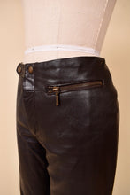 Load image into Gallery viewer, Vintage low rise dark brown leather moto pants are shown from the side. These pants have a zippered hip pocket.