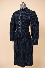 Load image into Gallery viewer, Vintage 1970's black and blue prairie midi dress by Lanz is shown from the side. This dress has bright aqua blue piping around the bust.