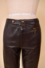 Load image into Gallery viewer, Vintage low rise dark brown moto pants are shown in close up. These brown leather low rise pants have moto style snap buttons at the waist.