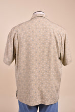 Load image into Gallery viewer, Vintage light tan button down short sleeve shirt is shown from the back. This shirt is a light tan with blue designs. 
