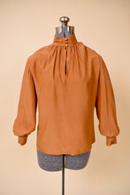 Load image into Gallery viewer, Vintage 1980&#39;s copper colored silk keyhole blouse is shown from the front. This blouse has three shiny buttons at the neckline. 
