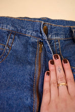 Load image into Gallery viewer, Vintage 80&#39;s blue denim worn jeans are shown in close up. These tapered leg jeans have a metal zipper. 
