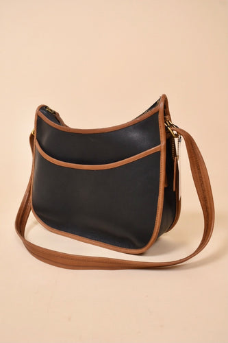 Vintage two tone black and brown leather 1980's Coach crossbody bag is shown from the front. This classic leather Coach purse is black with brown leather trim. 