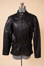 Load image into Gallery viewer, Vintage black leather cinched waist moto jacket is shown from the front. This jacket has a patchwork detail on the bust. 
