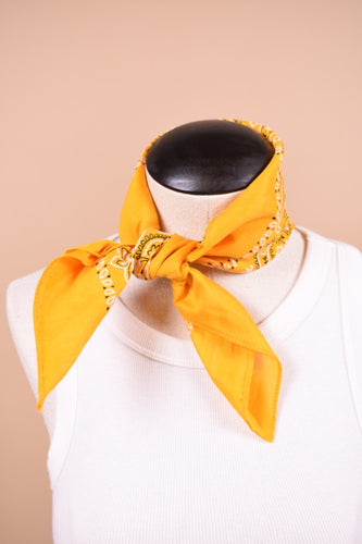Vintage paisley print yellow bandana is shown in close up. This bandana is styled tied around the neck.