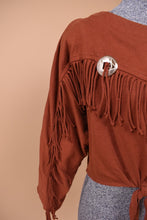 Load image into Gallery viewer, Vintage burnt orange cropped fringe top is shown in close up. This western style crop top has a silver coin accent.
