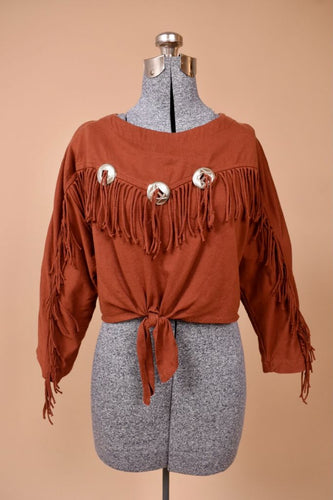 Vintage rust brown western style cotton cropped top is shown from the front. This shirt has fringe on the sleeves and across the chest.