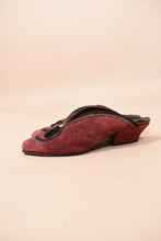 Load image into Gallery viewer, Red suede heeled slip on mules are shown from the side. These mules have black tassels on the front.
