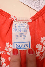 Load image into Gallery viewer, Closeup of 1970&#39;s red and white floral dress label. The label reads Made in USA, 50% polyester, 50% cotton, Size 14, Sears.
