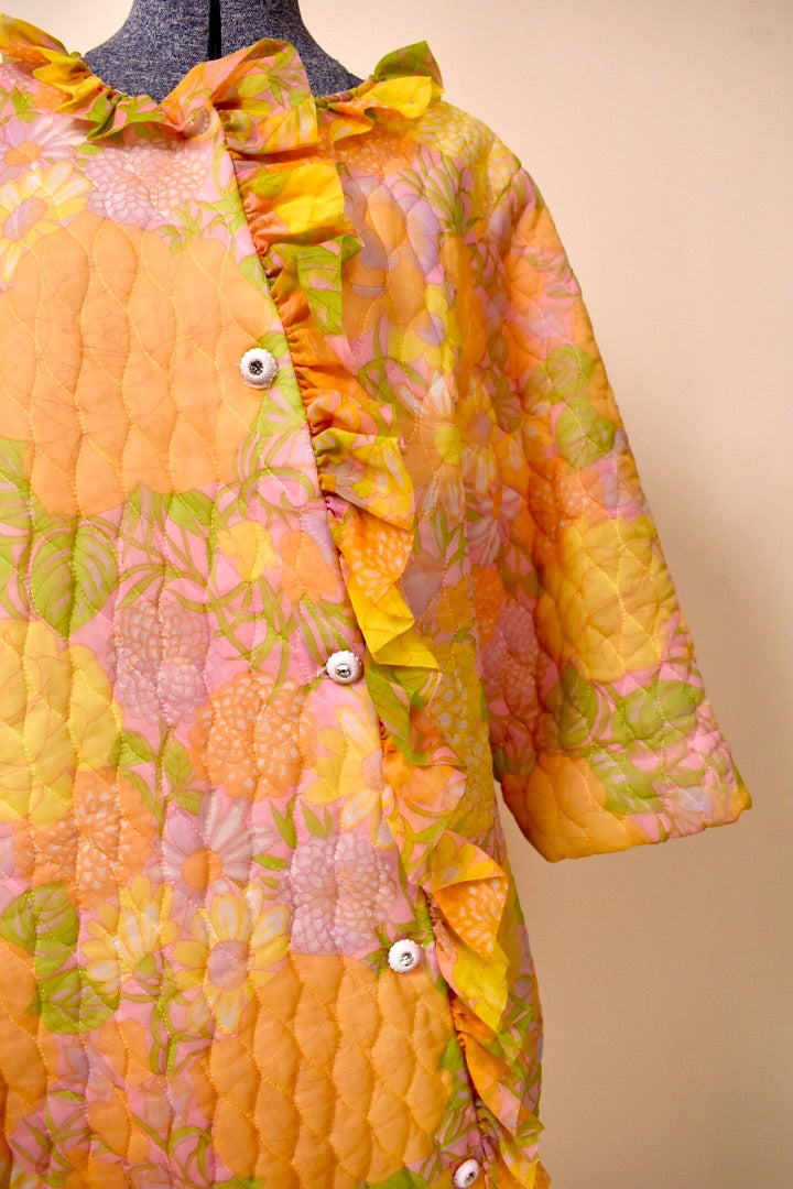 50s/60s Orange, Pink, and Yellow floral long bed jacket showing the detailed ruffle where the button closure is 