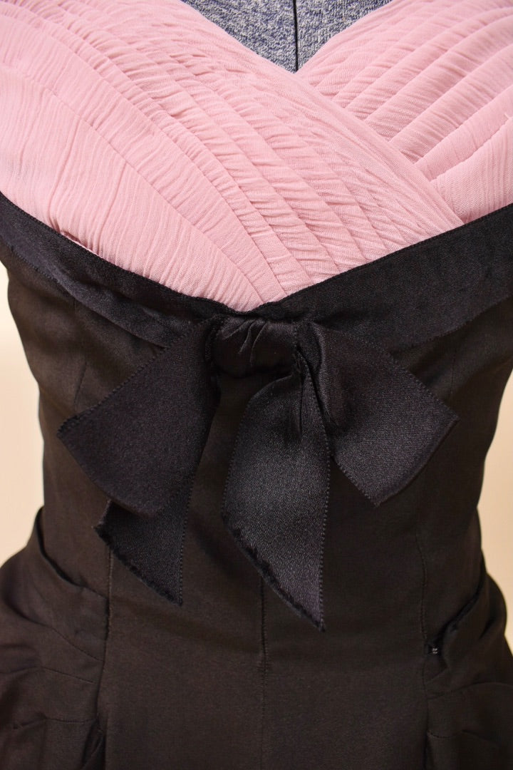 Front waist of black and pink dress is shown up close. The waist features a black bow.