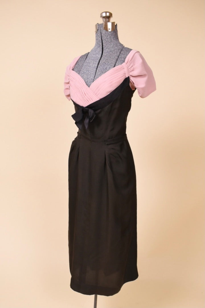 Black and pink dress is shown from the side. The sleeves are pleated.