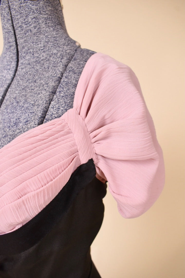Sleeve of the black and pink dress is shown up close. The sleeve is pleated.