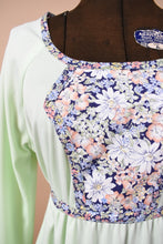 Load image into Gallery viewer, Vintage seventies mint green midi length dress is shown in close up. This dress has a navy and pink flower panel at the bust.
