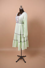 Load image into Gallery viewer, Vintage 70s handmade green prairie dress is shown from the side. This dress has long sleeves.
