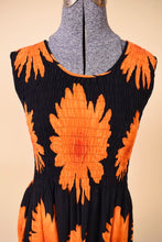 Load image into Gallery viewer, Y2K black and orange bright print flower print summer dress is shown in close up. This dress has a stretchy smocked top. 
