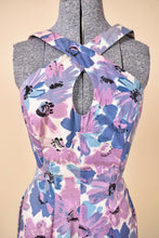 Load image into Gallery viewer, Vintage 1950&#39;s purple and blue painted floral print dress is shown in clsoe up. This dress has a cross front keyhole neckline. 
