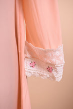 Load image into Gallery viewer, Vintage peachy pink sleep dress shown in close up. This nightgown has lace details at the sleeve with pink floral embroidery.
