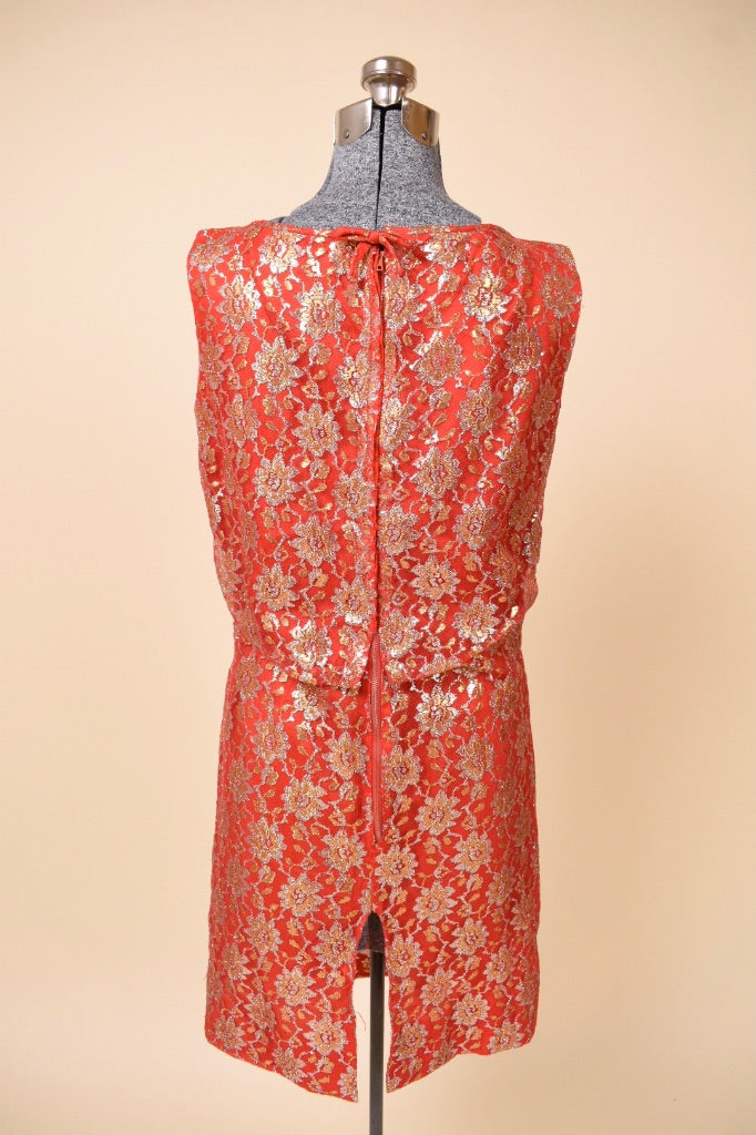 Vintage sixties red and lace metallic party dress is shown from the back. This dress has a slit at the back of the skirt. 