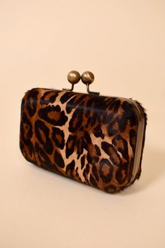 Vintage 1990's leopard print ponyhair clutch wallet is shown from the side. This clutch has brassy hardware.