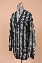 Load image into Gallery viewer, Vintage 80s dark green and white striped v neck cardigan sweater is shown from the side. This lambswool cardigan has buttons down the front. 
