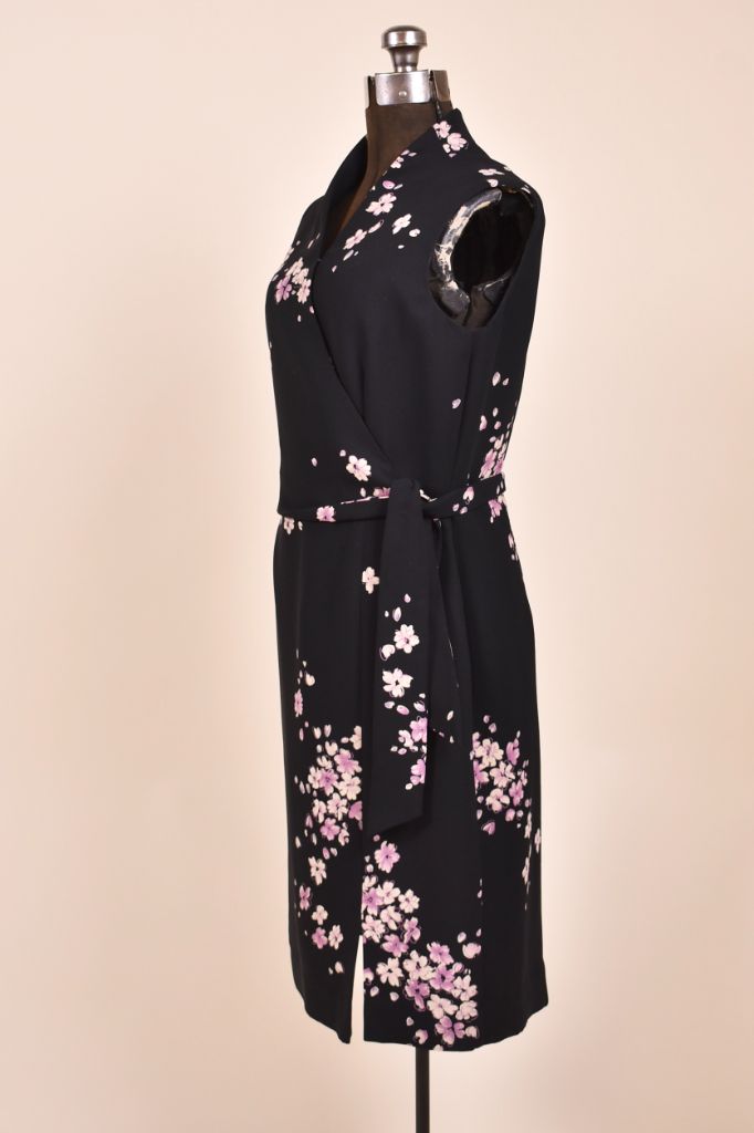Vintage black and pastel purple floral print dress is shown from the side. This wrap dress is sleeveless. 