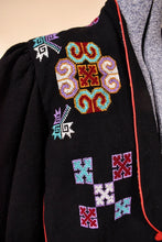 Load image into Gallery viewer, Vintage eighties black bolero jacket is shown in close up. This jacket has geometric embroidered cross stitch designs. 
