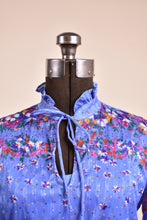 Load image into Gallery viewer, Vintage blue polyester floral print dress is shown in close up. This dress ties in a bow at the neckline. 
